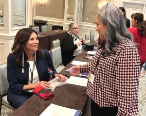 The DOJ’s Native American Outreach Services Liaison, Marlys Big Eagle (who served as a keynote speaker), discusses her MMIP work with AIIC Program Manager Tyesha Wood. {Photo credit: AATTAP}