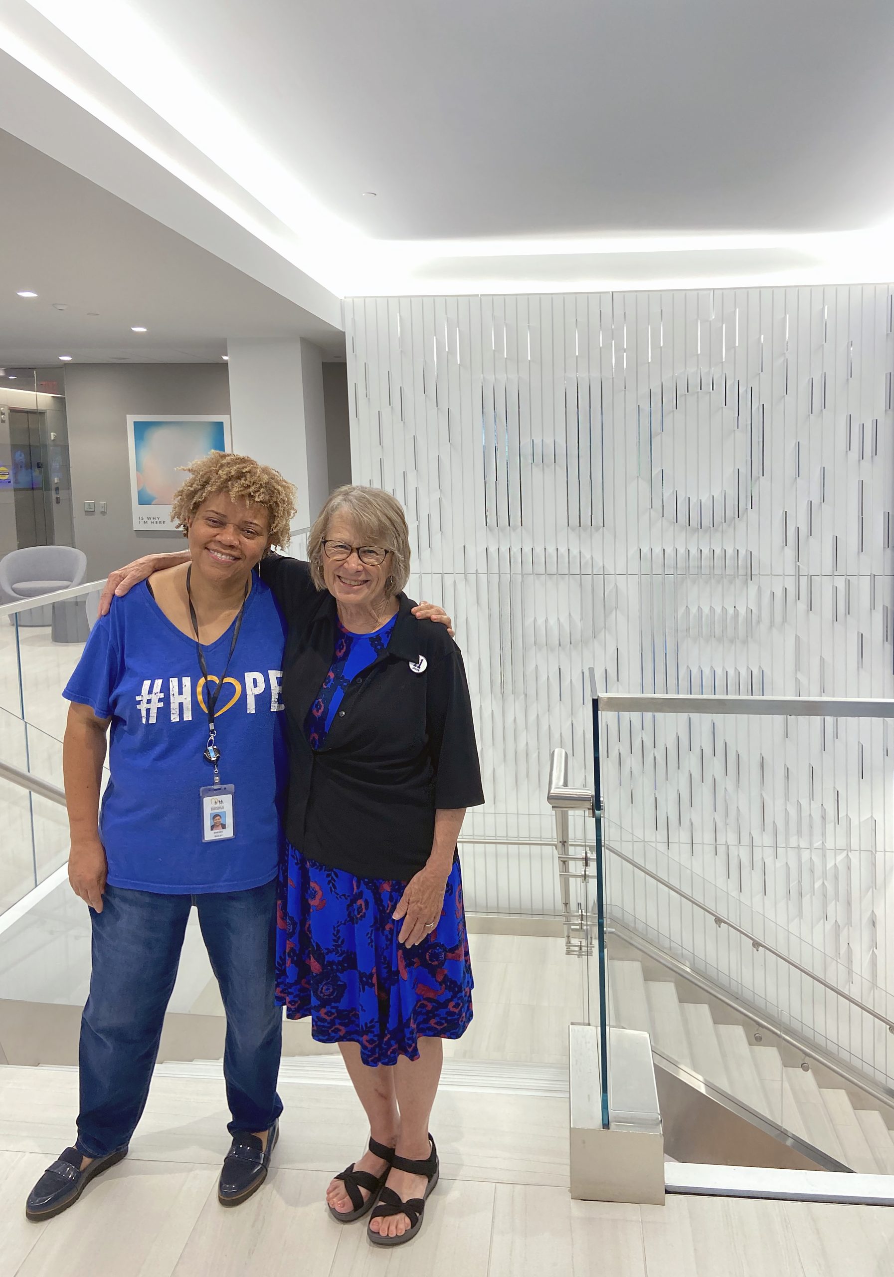 Foto de dos mujeres con este pie de foto: Patty Wetterling (derecha) saluda a la Directora de Proyectos Especiales del NCMEC, Sherry Bailey, durante la visita de la familia de supervivientes a la sede del NCMEC en Arlington, Virginia.