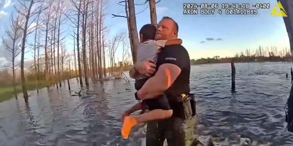 Photo of boy with arms wrapped around rescuer as he is carried from a pond. Caption for photo reads: The child clung tightly as Deputy Wes Brough carried him to safety. Brough received an email from the boy’s out-of-state relatives who watched the rescue footage. “They said that they could tell how thankful he was by the way he touched my face,” Brough says.