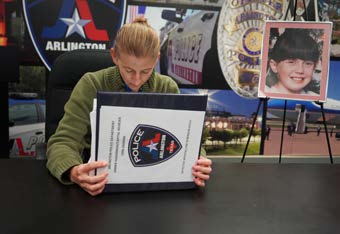 Detective Krystalynne Robinson looking through evidence binder with picture of Amber Hagerman on easel behind her