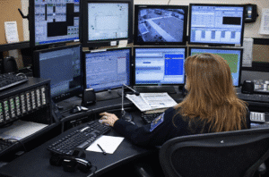 Operador del 911 trabajando en un ordenador con 8 pantallas de información