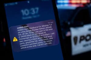 Mobile phone displaying wireless alert with a police car in background