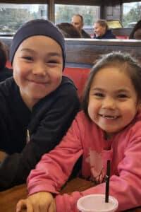 Two smiling little girls at a fast-casual restaurant--Ashley Johnson Barr and her sister Amber Barr