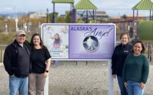 Four people near a sign that reads "Alaska's Angel"--at Ashley Johnson-Barr Memorial Park