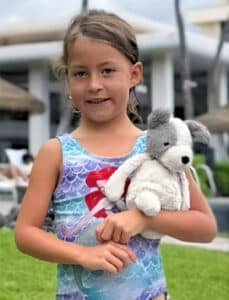 Violet C., recovered using Arizona's first Turquoise Alert, stands holding a stuffed animal outdoors in Hawaii.