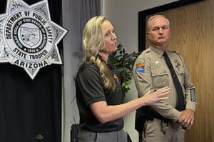 Arizona Department of Public Safety Alerts Coordinator Kelsey Commisso addresses the media after the successful recovery whiles standing next to a state trooper and in front of a Department of Public Safety badge sign.