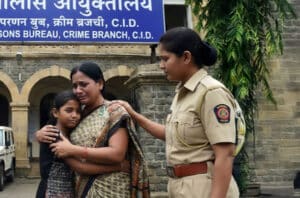 Mumbai India female police officer with a mother and daughter in front of a public safety building.