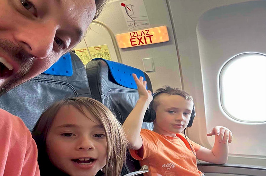 Father and two children take a selfy while flying on a commercial airline