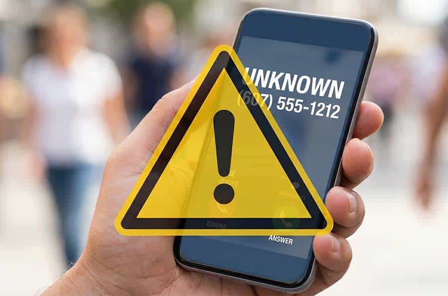 Cell phone with Unknown and a fake number on screen with warning symbol triangle over the top