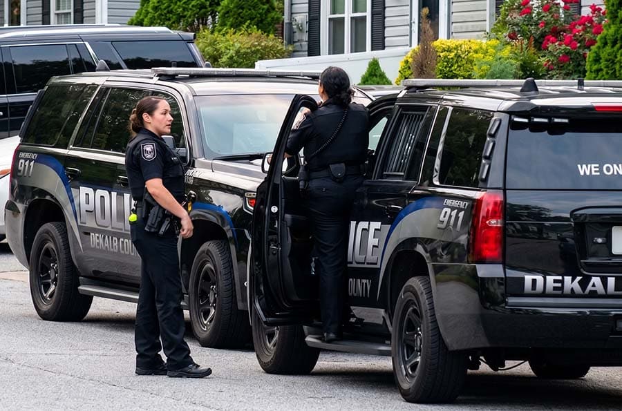 Two female Dekalb County Georgia Police talking as one climbs into an SUV police cruiser.