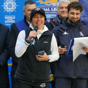 Lisa Vorrasi speaking at Special Olympics World Games with men standing behind her on stage.