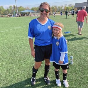 Lisa Vorrasi with son, both are dressed in soccer gear and standing in soccer field.