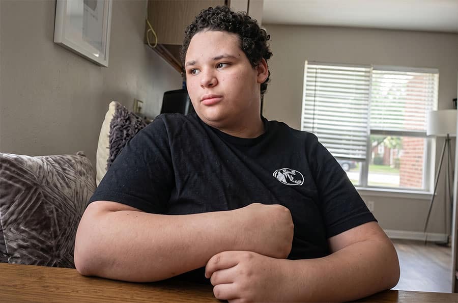 Teenage boy looking out window from living room