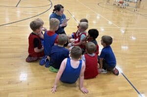 Lieutenant Jenna Clawson Huibregtse coaching two teams of five young boy basketball teams.