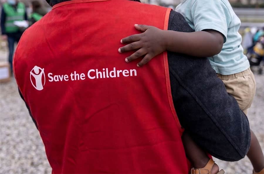 Save The Children worker carrying child