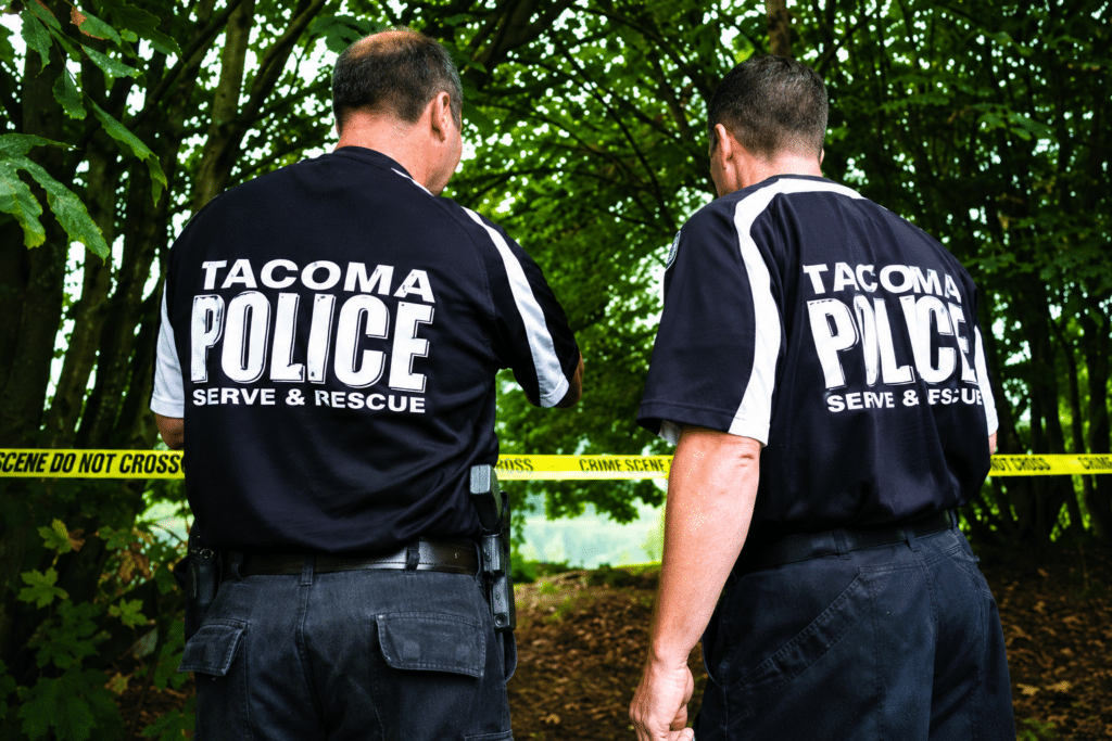 Photo of the back of two men and their shirts, which read "Tacoma Police"
