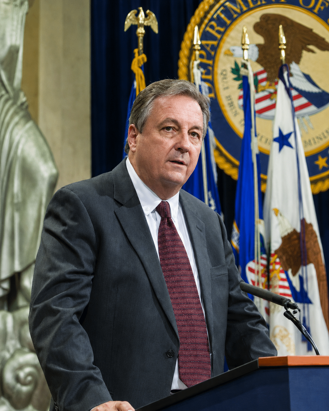 Man (Mark Simpson) standing at podium