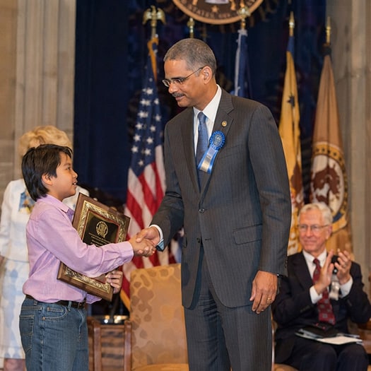 Attorney General Eric Holder congratulating a child during Missing Children's Day event
