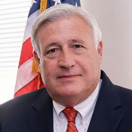 Portrait of Bill Bryan standing in front of the U.S. flag